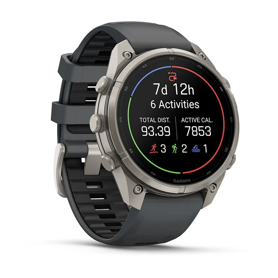 A Garmin smartwatch with a dark gray silicone strap and a silver-toned metal case, shown at a three-quarter angle on a clean white background. The watch face displays fitness metrics.