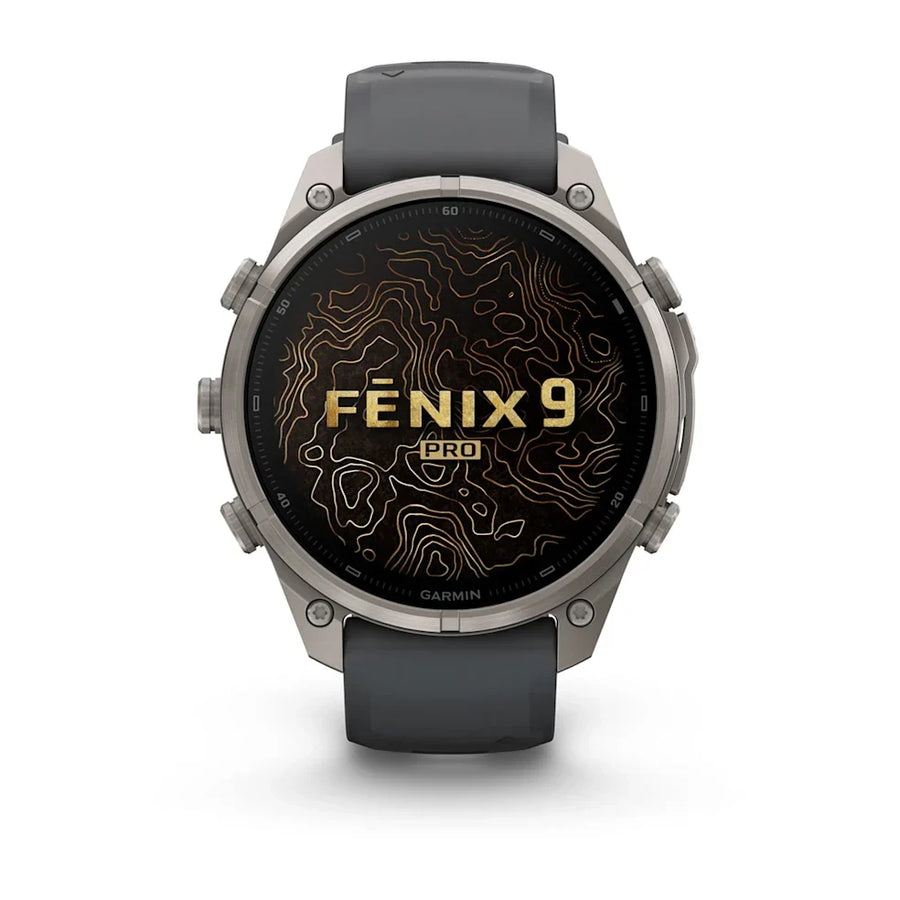 A Garmin Fenix 9 Pro smartwatch with a dark gray silicone strap and a silver-toned titanium case, featuring a black watch face with gold topographic lines and the text 'FENIX 9 PRO'.