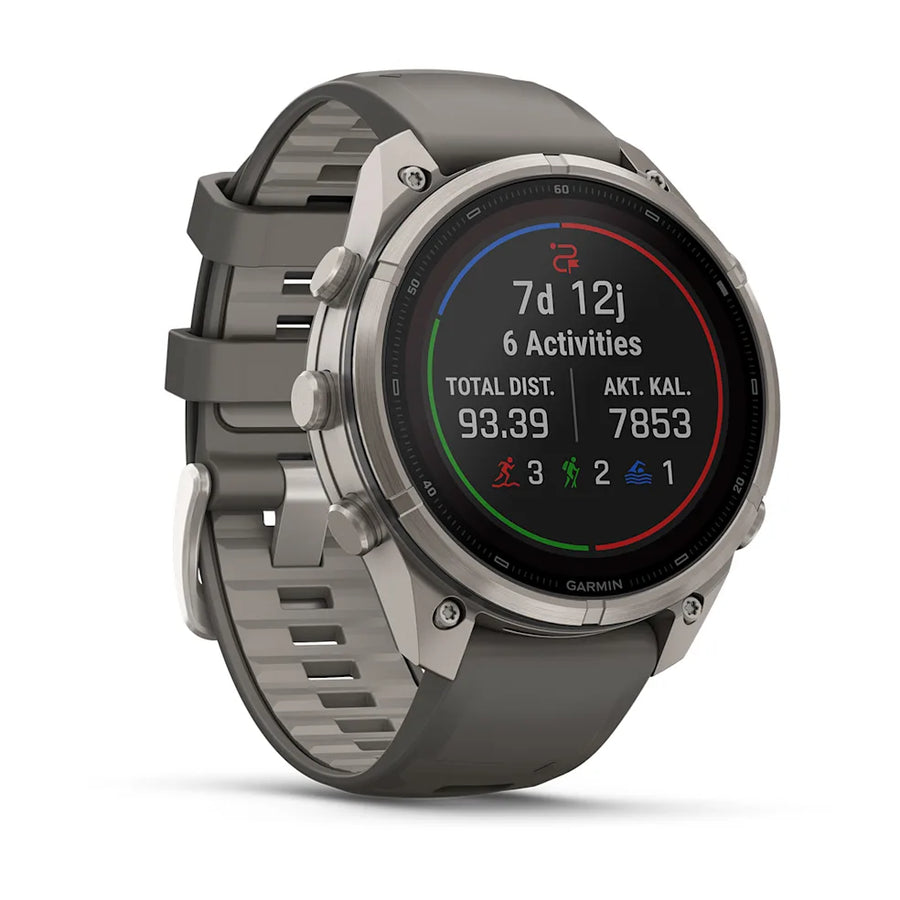 A Garmin smartwatch with a dark gray silicone strap and a silver-toned metallic case, shown at a three-quarter angle on a clean white background.